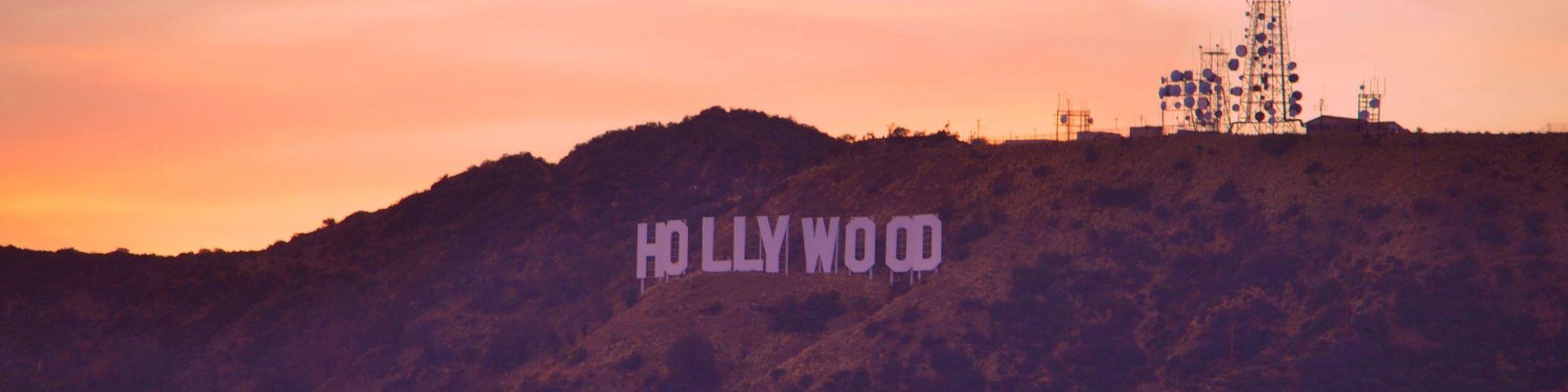 The image features the iconic Hollywood sign on a hill with a radio antenna nearby, set against a beautiful sunset sky.