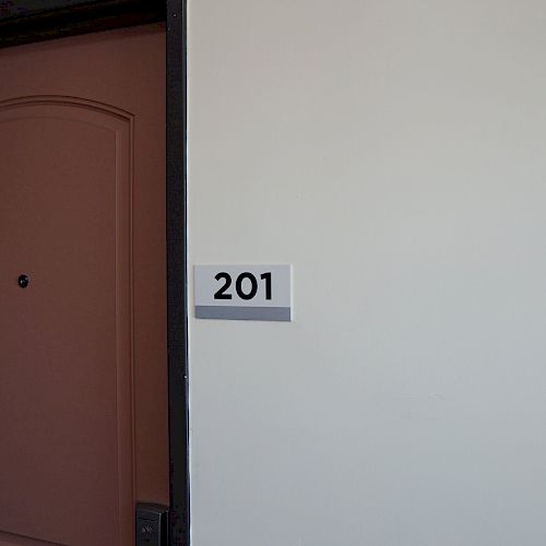 The image shows a brown door next to a wall with a sign that reads 